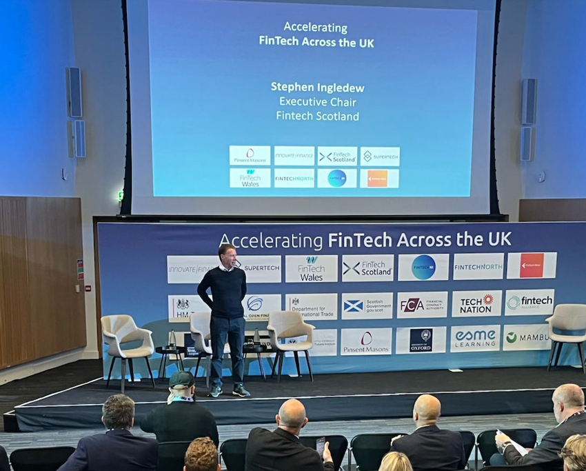 A person standing on a stage in front of a large screen

Description automatically generated with medium confidence